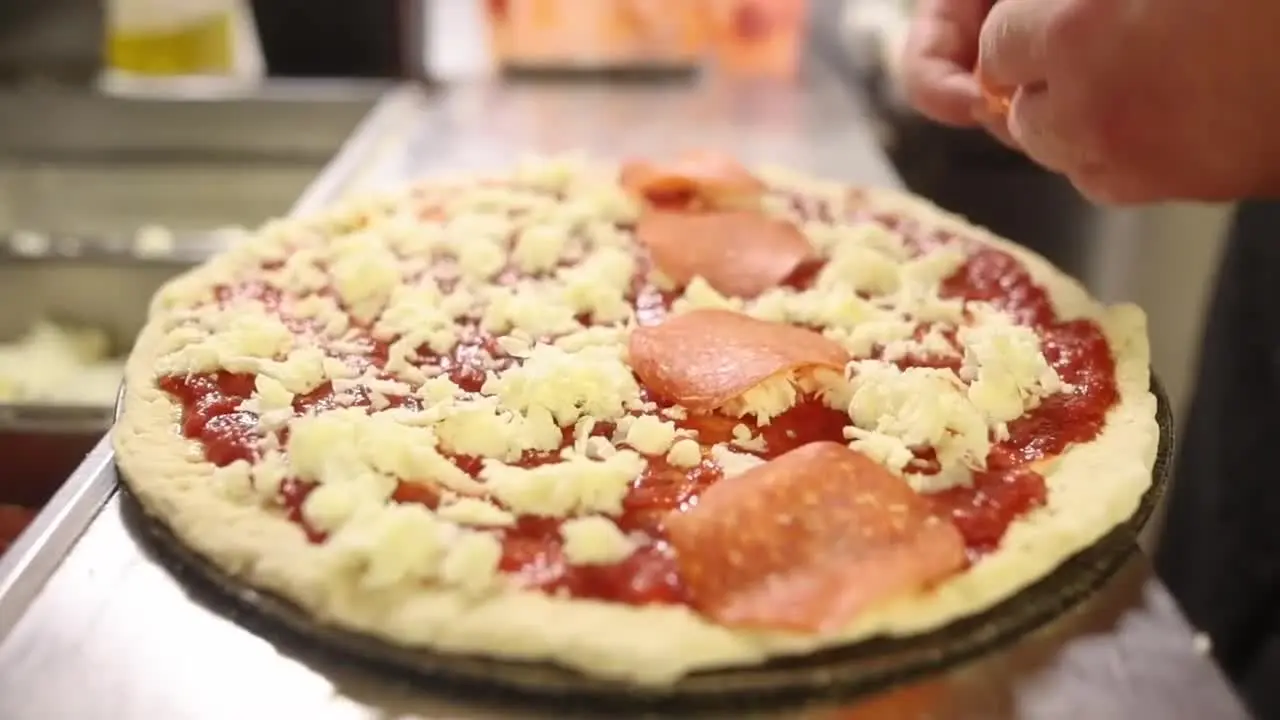 A Ben and Jay's pizza being topped before baking